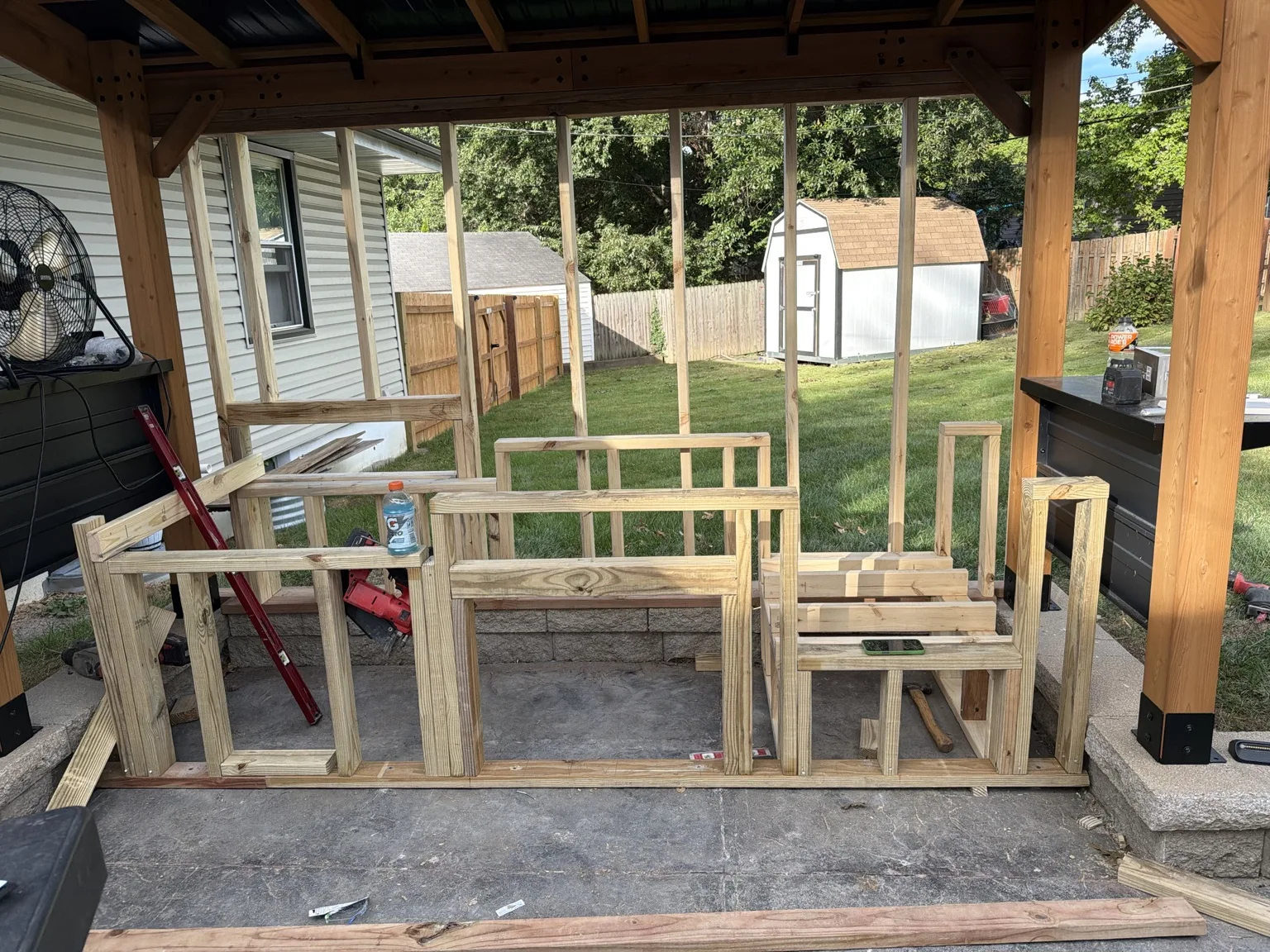 Wood framing for an outdoor kitchen beneath a patio cover