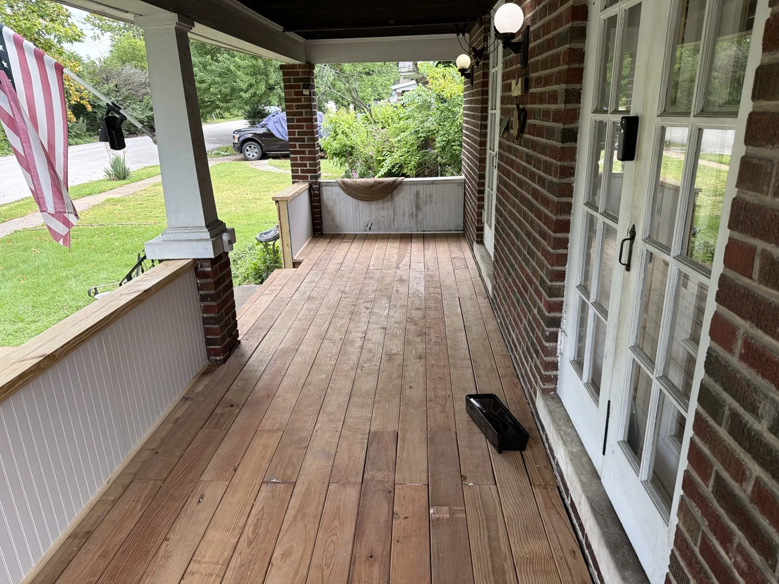 Wood flooring along a covered brick porch